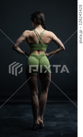 Young beautiful woman with athletic body on dark background. Fitness girl 126245428
