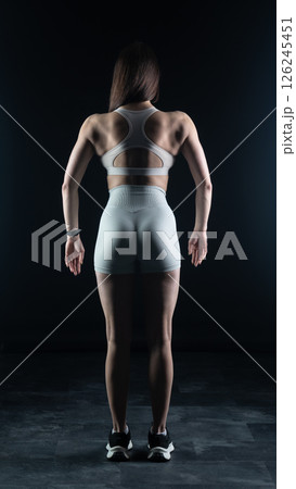 Young beautiful woman with athletic body on dark background. Fitness girl 126245451