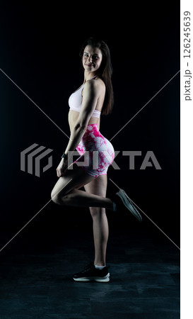 Young beautiful fitness woman on a black background. Fitness girl, female bodybuilder on a dark background 126245639