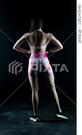 Young beautiful fitness woman on a black background. Fitness girl, female bodybuilder on a dark background Young beautiful fitness woman on a black background. Fitness girl, female bodybuilder on a dark background 126245640