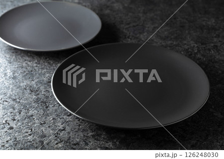 Black ceramic plates on a black stone table. 126248030