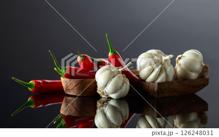Garlic bulbs and red chili peppers on a black background. 126248031