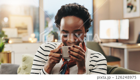 Black woman, relax and coffee aroma in home to start morning, warm scent and caffeine satisfaction. Smile, person and smell hot beverage on sofa with nostalgia, thinking or weekend break in apartment 126248975
