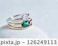 Elegant diamond and emerald rings displayed on a soft white background. Beautiful rings with diamond and emerald stones, showcasing exquisite craftsmanship on a white textured setting. 126249113