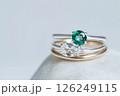 Elegant diamond and emerald rings displayed on a soft white background. Beautiful rings with diamond and emerald stones, showcasing exquisite craftsmanship on a white textured setting. 126249115