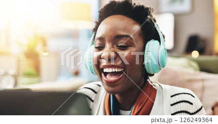 Headphones, black woman and laughing with laptop in home for comedy movie, funny video and comic film. Relax, person and streaming subscription for social media meme, podcast joke and entertainment 126249364