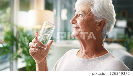 Home, drinking water and senior woman with smile, wellness or hydration with morning routine. Nutrition, pensioner or elderly person in lounge, thirsty or liquid with health in retirement or relaxing 126249376