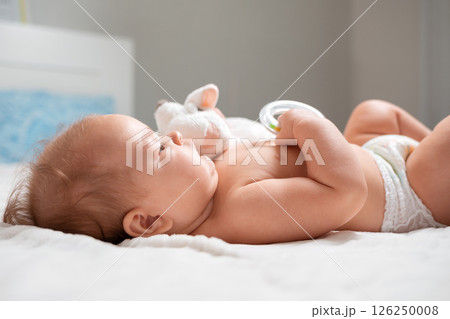 A baby is lying with a toy in the cradle. Close-up. The concept of parenthood A baby is lying with a toy in the cradle. Close-up. The concept of parenthood 126250008