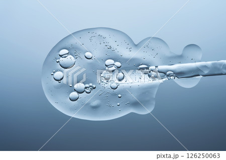 Transparent serum with bubbles and dropper dropper on a blue background. Transparent serum with bubbles and dropper dropper on a blue background. 126250063