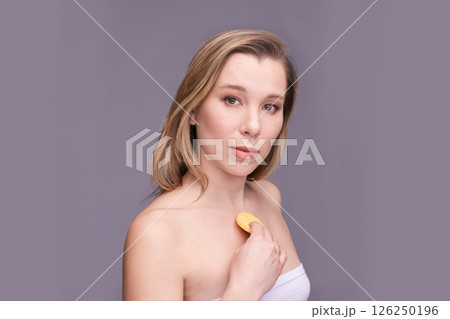 Caucasian young female holding skincare product against chest with neutral Caucasian young female holding skincare product against chest with neutral 126250196