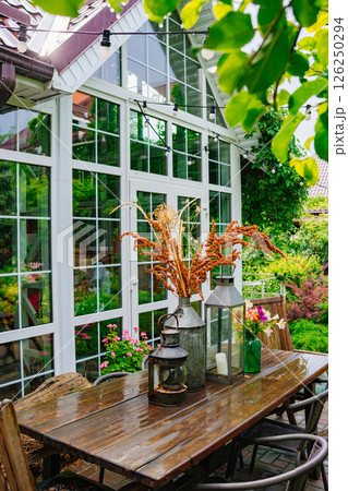 wooden table with lanterns and dried flowers. The yard in the house. 126250294