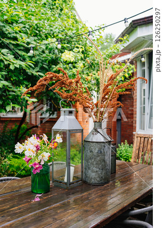 wooden table with lanterns and dried flowers. The yard in the house. 126250297