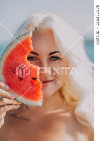 Watermelon Woman Summer Beach: Portrait of a blonde woman holding a watermelon slice near the ocean, enjoying summer. Watermelon Woman Summer Beach: Portrait of a blonde woman holding a watermelon slice near the ocean, enjoying summer. 126251536