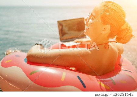 Woman laptop sea. Freelancer woman in sunglases floating on an inflatable big pink donut with a laptop in the sea. People summer vacation rest lifestyle concept Woman laptop sea. Freelancer woman in sunglases floating on an inflatable big pink donut with a laptop in the sea. People summer vacation rest lifestyle concept 126251543