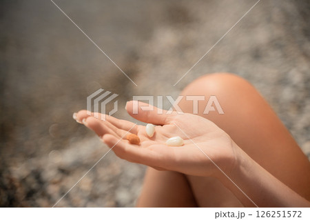 A person is holding a handful of nuts in their hand. The nuts are of different sizes and shapes, and they appear to be almonds. The person seems to be enjoying the nuts and is likely to eat them soon. A person is holding a handful of nuts in their hand. The nuts are of different sizes and shapes, and they appear to be almonds. The person seems to be enjoying the nuts and is likely to eat them soon. 126251572
