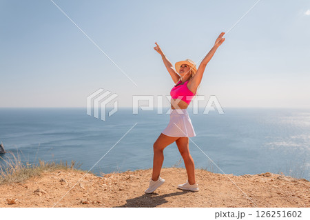 A woman in a pink top and white skirt is standing on a beach 126251602