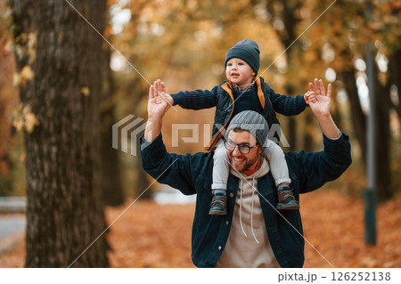 In warm clothes. Father and young son is together outdoors at daytime 126252138