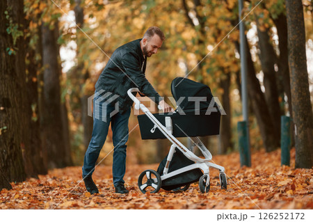 Man with pram is having a walk in the autumn park 126252172