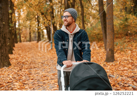 Enjoying the nature. Man with pram is having a walk in the autumn park 126252221