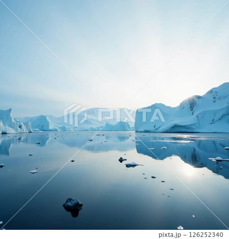 Calm waters mirror massive icebergs as the sun rises over the Arctic. The scenery evokes a sense of peace, isolation, and the beauty of nature in the wild Generative AI 126252340