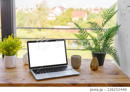 Laptop computer with white screen on wooden desk on window background. Mockup, template, copy space Laptop computer with white screen on wooden desk on window background. Mockup, template, copy space 126252440