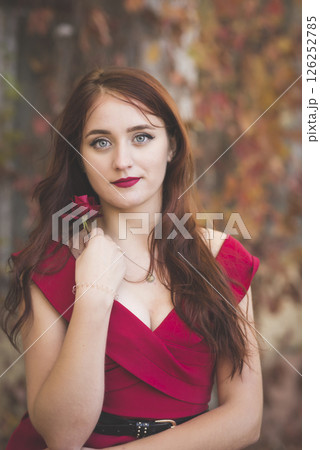 portrait of a young girl in a red dress against the background of autumn trees with a rose portrait of a young girl in a red dress against the background of autumn trees with a rose 126252785