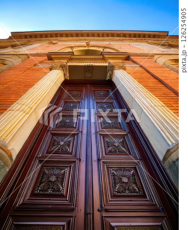 Grand entrance of historic building with ornate wooden doors under clear blue sky. Generative AI 126254905