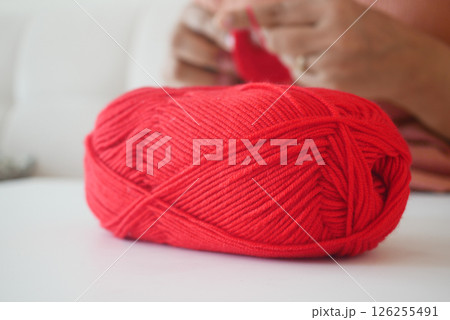 Bright red yarn ball on a table during a cozy crafting session Bright red yarn ball on a table during a cozy crafting session 126255491