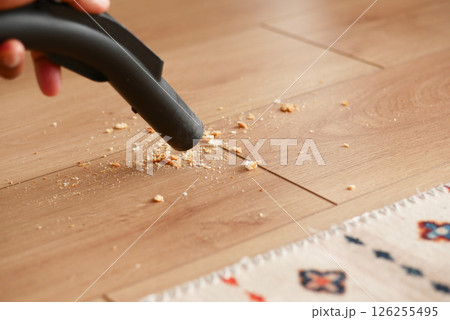 Cleaning crumbs from wooden floor using a vacuum cleaner 126255495