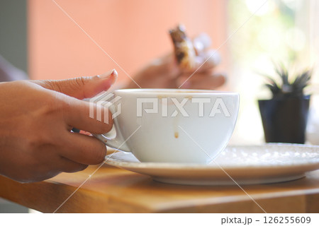 Enjoying a warm coffee while savoring a sweet treat in a cafe 126255609