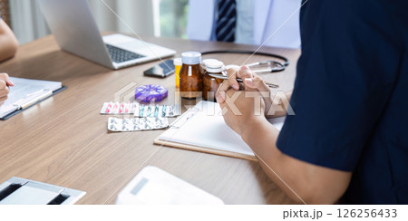 Doctor Team Meeting. Focused healthcare professionals engaged in medication planning. 126256433