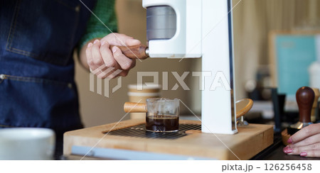 Sustainability and Coffee Preparation. A barista using a coffee machine to brew sustainably sourced coffee. Sustainability and Coffee Preparation. A barista using a coffee machine to brew sustainably sourced coffee. 126256458