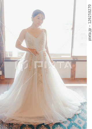 白いドレスをまとい、自然光の中でこちらを見つめる女性 126258270