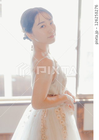 白いドレスをまとい、自然光の中でこちらを見つめる女性 126258276