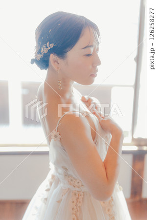 白いドレスをまとい、自然光の中でこちらを見つめる女性 126258277