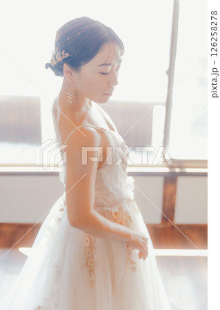 白いドレスをまとい、自然光の中でこちらを見つめる女性 126258278
