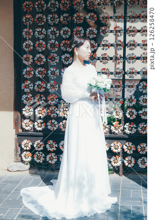 和風の花装飾を背景に立つウェディングドレス姿の女性のポートレート 126258470