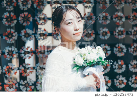 和風の花装飾を背景に立つウェディングドレス姿の女性のポートレート 126258472