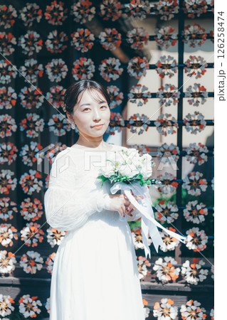 和風の花装飾を背景に立つウェディングドレス姿の女性のポートレート 126258474