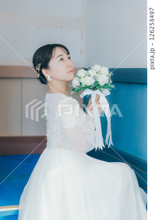 階段に座って振り返るウェディングドレス姿の女性のポートレート 階段に座って振り返るウェディングドレス姿の女性のポートレート 126258497