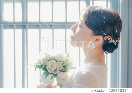 白いドレスを着た女性が窓際に立つシルエット風ポートレート 126258534