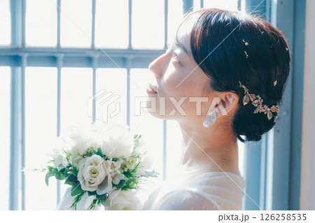 白いドレスを着た女性が窓際に立つシルエット風ポートレート 126258535