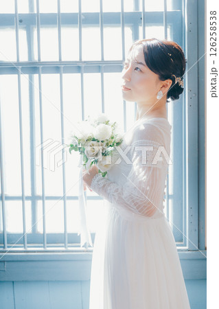 白いドレスを着た女性が窓際に立つシルエット風ポートレート 白いドレスを着た女性が窓際に立つシルエット風ポートレート 126258538