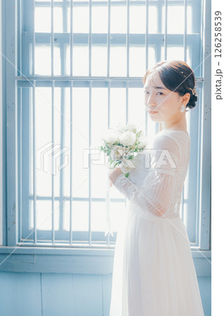 白いドレスを着た女性が窓際に立つシルエット風ポートレート 白いドレスを着た女性が窓際に立つシルエット風ポートレート 126258539