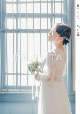 白いドレスを着た女性が窓際に立つシルエット風ポートレート 白いドレスを着た女性が窓際に立つシルエット風ポートレート 126258540
