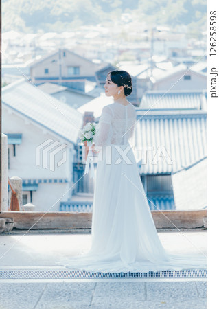 高台の神社から町並みを望むウェディングドレス姿の女性のポートレート 126258598