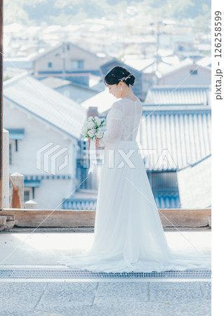 高台の神社から町並みを望むウェディングドレス姿の女性のポートレート 126258599