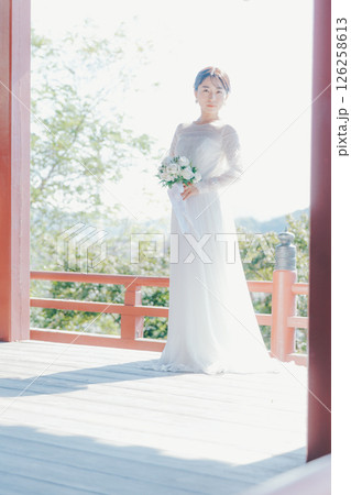 高台の神社から町並みを望むウェディングドレス姿の女性のポートレート 高台の神社から町並みを望むウェディングドレス姿の女性のポートレート 126258613