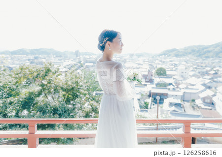 高台の神社から町並みを望むウェディングドレス姿の女性のポートレート 高台の神社から町並みを望むウェディングドレス姿の女性のポートレート 126258616