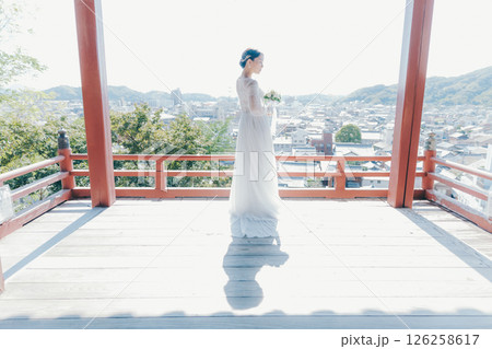 高台の神社から町並みを望むウェディングドレス姿の女性のポートレート 126258617